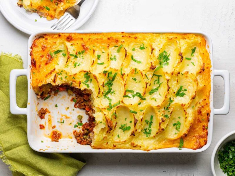 Lasaña sin gluten hecha con papas laminadas, relleno de verduras y salsa vegetal, servida en plato blanco como alternativa sin harina